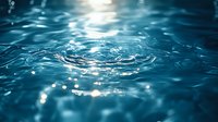 Macro shot of water droplets and ripples with sunlight reflecting off the surface, creating shimmering bokeh effects. Suitable for backgrounds, wellness, and nature designs.