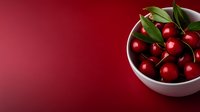 Fresh red cherries with green stems in white ceramic bowl on burgundy background for culinary and food photography projects.