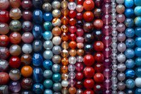 Colorful collection of shiny glass beads arranged in rows creating abstract pattern background, perfect for jewelry making and craft projects designs.