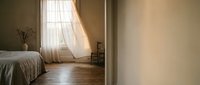 Serene bedroom interior with natural light streaming through sheer curtains, wooden flooring, and minimalist decor for home design and lifestyle projects.