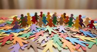 Colorful paper cutout figures standing together representing diversity, teamwork and community unity for social projects and inclusion campaigns.