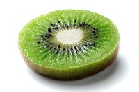 Fresh juicy kiwi fruit slice showing vibrant green flesh with black seeds and white center on white background, isolated for food design projects.