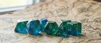 Blue and green translucent polyhedral gaming dice set arranged on vintage map background for tabletop role-playing games and board game adventures.