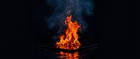Dramatic orange flames erupting from metal fire bowl against starry night sky background creating mystical campfire atmosphere for outdoor adventure concepts.