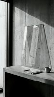 Minimalist concrete workspace with transparent acrylic award trophy, notebook and coffee cup in natural window light for modern office interior design.
