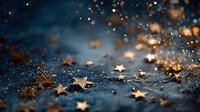 Golden star confetti scattered on dark blue textured surface with magical bokeh lights creating festive holiday atmosphere.