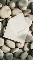 Open white envelope resting on smooth river stones creating natural spa-like composition for wellness and communication concepts.