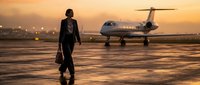 Professional businesswoman walking towards private jet at sunset airport tarmac for luxury travel and corporate aviation concepts.