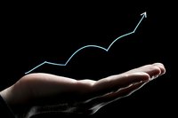 Hand holding a glowing blue rising arrow chart on dark background, symbolizing financial growth, investment success and business profit.