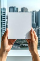Hands holding blank white card with urban skyline cityscape background, mockup for branding, advertising, and marketing design projects.