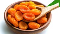 Fresh dried apricots in wooden bowl and spoon on white background, bright orange organic fruit for healthy snacking and cooking, isolated setup for food photography.