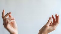 Two elegant female hands with manicured nails positioned gracefully against clean white background, expressing gentle gestures for beauty and wellness concepts.