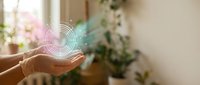 Hands cupped holding glowing digital sound waves in bright home interior with plants, representing audio technology and music streaming concepts.
