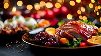 Glazed roasted duck with citrus fruits and grapes on dark plate against festive bokeh lights background, holiday dinner serving with garnish and sauce.