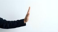 Hand gesture showing stop sign with palm facing forward against white background for business communication and body language concepts.