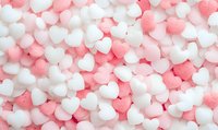 Pink and white heart-shaped sugar candies creating romantic pattern background. Sweet confectionery texture for Valentine's Day and love themes.