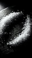 White sea salt crystals scattered on dark wet surface with water droplets, creating contrast in monochrome composition for culinary and food styling projects.