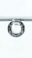 Crystal clear water droplet suspended on glass surface against white background, isolated for design and commercial use.