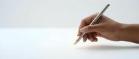 Hand holding wooden pencil ready to write or draw on clean white paper surface with copy space for creative projects and educational content.