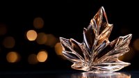 Crystal maple leaf ornament with warm golden bokeh lights creating festive autumn holiday atmosphere for seasonal decorating and home decor projects.