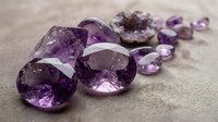 Purple amethyst gemstones and crystals scattered on neutral background for jewelry making, healing practices, and luxury design projects.
