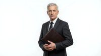 Middle-aged Caucasian male professional businessman wearing dark suit and tie, holding brown leather briefcase, isolated on white background for corporate and business use.