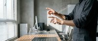 Professional businessman using smartphone in modern office workspace with natural lighting and contemporary interior design for business communication.