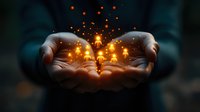Magical glowing golden light particles floating above cupped hands in darkness, creating mystical atmosphere with sparkles and warm illumination effect.