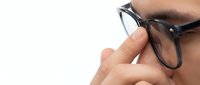 Close-up of male hand adjusting black-framed eyeglasses against white background. Suitable for optometry, vision care, eyewear advertising, and healthcare marketing materials.