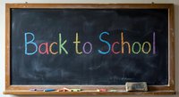 Back to School written in colorful chalk on dark blackboard with wooden frame and chalk pieces, education concept for classroom learning.