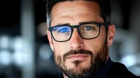 Confident middle-aged Caucasian businessman with beard and glasses looking directly at camera with genuine smile. Professional corporate headshot style portrait.