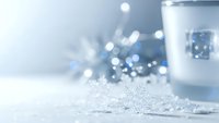 Winter holiday scene with delicate snowflakes on white surface and soft bokeh lights creating magical festive atmosphere for seasonal decorations.