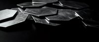 Broken glass fragments scattered on dark surface creating dramatic shadows and reflections in monochrome black and white photography for design projects.