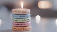 Stack of colorful macarons with burning candle on top against blurred background, celebrating special occasion or birthday party.
