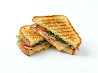 Toasted sandwich with ham, cheese, tomato and lettuce on white background, isolated and ready for menu design, restaurant marketing, food delivery apps and culinary publications.
