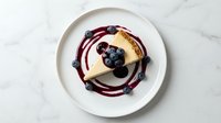 Gourmet dessert with vanilla panna cotta, fresh blueberries and berry coulis on white plate. Fine dining restaurant presentation for menu design.