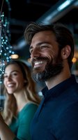 Happy bearded man smiling with woman in background at modern restaurant or bar with bokeh lights creating warm atmosphere for dining and socializing.