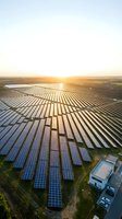 Aerial view of expansive solar panel farm at sunset with rows of photovoltaic cells stretching across flat landscape, renewable energy generation facility for sustainable power production.