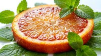 Sliced grapefruit half with fresh mint leaves on white background, suitable for food photography, culinary design, wellness and nutrition content.
