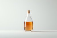 Elegant teardrop glass bottle with amber liquid and cork stopper on minimalist white background, perfect for premium beverage or oil packaging.