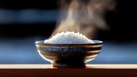 Steaming hot white rice served in traditional ceramic bowl against dark background, dramatic lighting highlights rising steam and texture of freshly cooked grains.