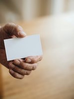Close-up of male hand holding blank white business card against blurred background. Suitable for corporate branding, networking, and professional identity concepts.