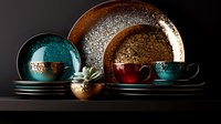 Elegant dinnerware set with turquoise and copper plates, cups and bowls featuring metallic patterns against dark background, modern tableware collection display.
