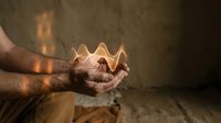 Hands cupping glowing paper boat on wooden surface with warm candlelight creating magical atmosphere for hope and dreams concepts.