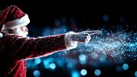 Magical winter scene with person in red Santa costume spreading glowing snow powder against dark background with blue bokeh lights creating festive atmosphere.