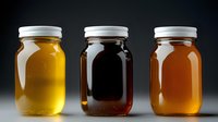 Three glass mason jars filled with different varieties and shades of honey or maple syrup arranged in row showing golden to dark amber colors against black background.
