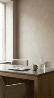 Minimalist workspace with wooden desk, neutral upholstered chairs, and natural light from window. Includes notebook, ceramic mug, and glass water carafe for office or home study design projects.