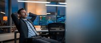 Exhausted businessman relaxing in office chair after long day of financial trading and data analysis in modern workplace.