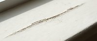 Crack in white painted wooden surface showing damage and wear, suitable for construction, renovation, and home repair design projects.