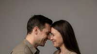 Happy couple touching foreheads in intimate moment showing love and connection on neutral background for relationship concepts.
